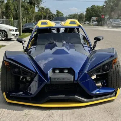 A black Slingshot with a yellow bumper and hood