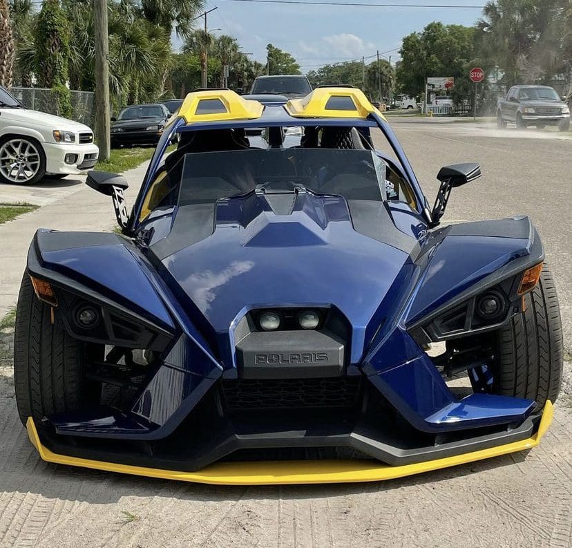 A black Slingshot with a yellow bumper and hood